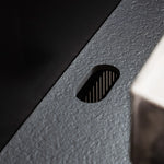 Detail of the cable grommet integrated into the black ceramic worktop Pilotis.\n::visuel:noir