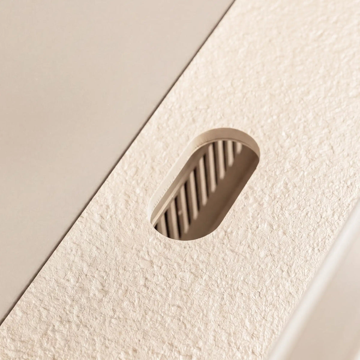 Detail of the cable grommet integrated into the white Pilotis ceramic worktop.\n::visuel:creme