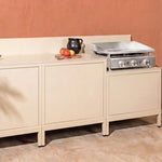 Cream-white Pilotis outdoor kitchen with integrated Vivaplancha griddle.\n::visuel:creme