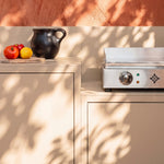 Cream-white outdoor kitchen Pilotis with Vivaplancha griddle and white ceramic worktop.
::visuel:creme