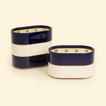 Bougies Totem L Bleu marine – Citronnelle & Sel de mer et Beige ivoire – Citronnelle & Citron, deux grandes bougies ovales à triple mèche en bois, posées sur un fond beige clair.