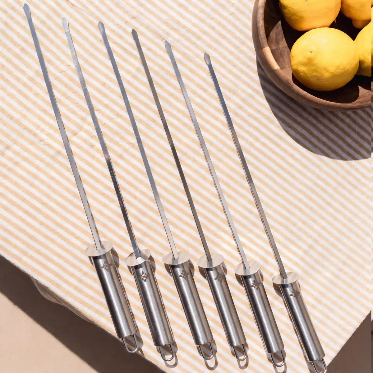 Brochettes Vivaplancha disposées sur un linge de table à côté de citrons