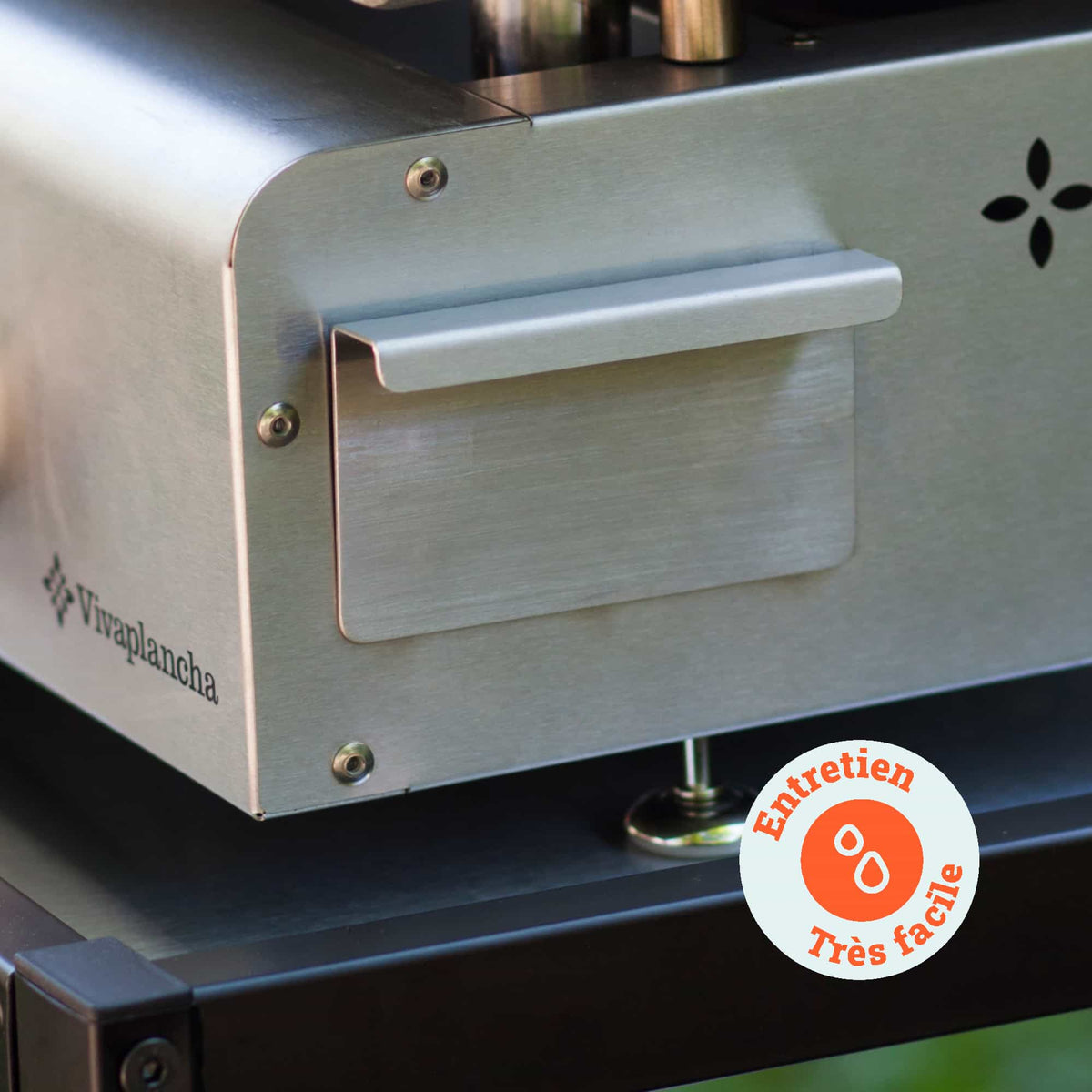 Close-up of the stainless steel grease collector on a Vivaplancha plancha, with an “Very easy maintenance” label indicating how simple it is to clean.