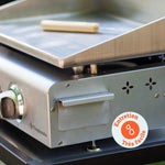 Close-up of the Vivaplancha griddle showing the stainless steel grease collector and a cleaning tool placed on the plate, with a badge reading “Very easy maintenance”.