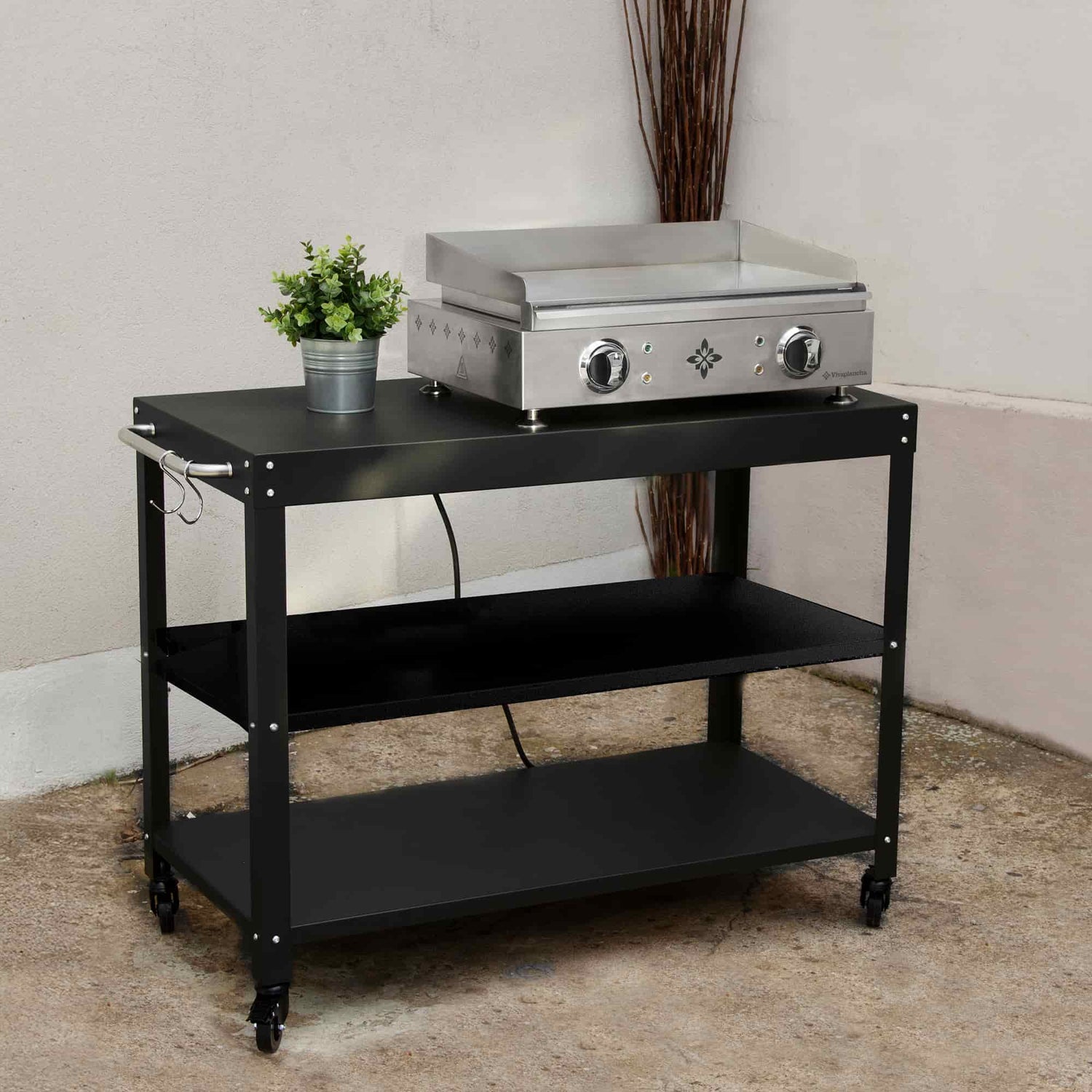 Black trolley for griddle with three storage levels, shown outdoors with a stainless steel electric griddle placed on the top shelf and a small decorative plant pot.