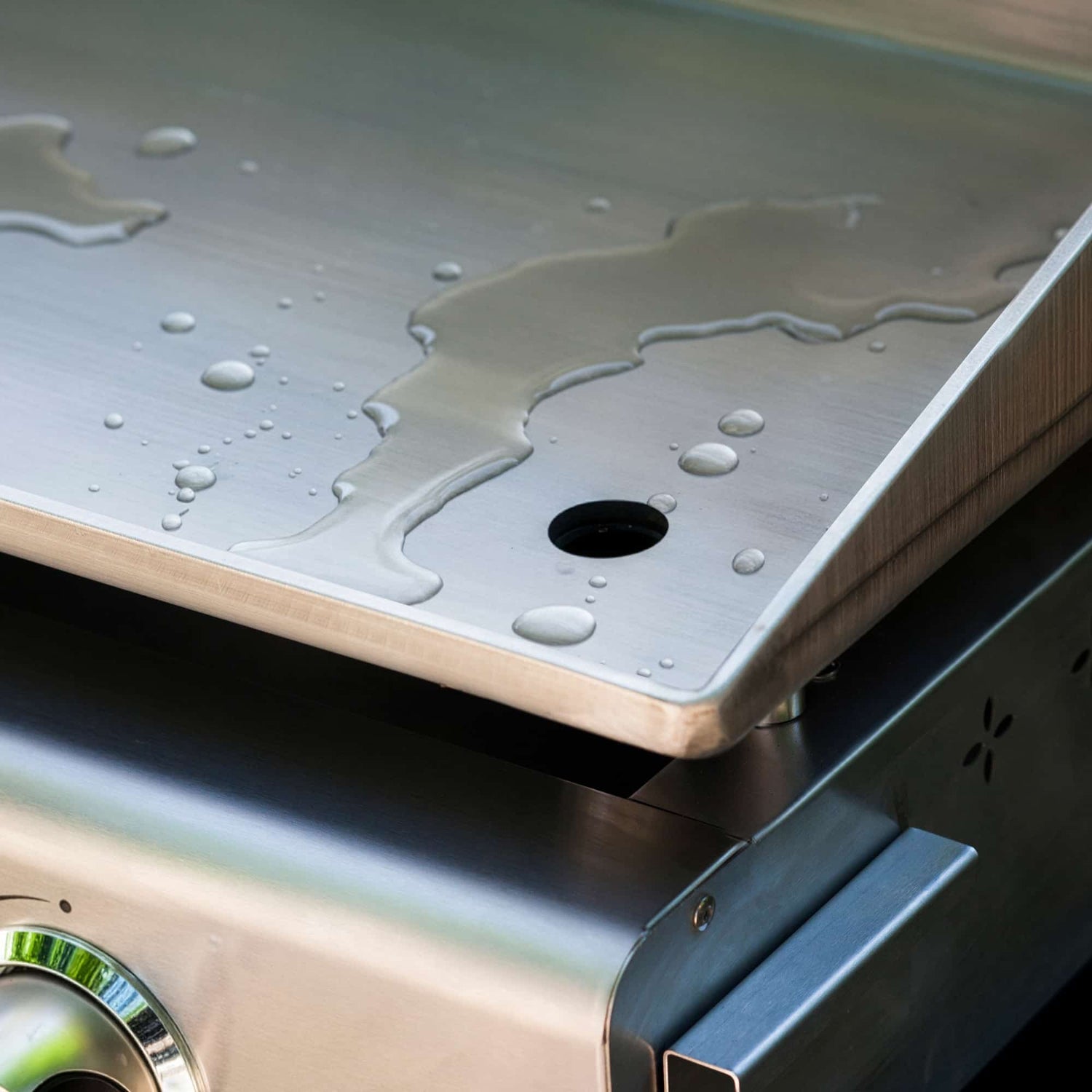 Rinsing the cooking plate of a Vivaplancha griddle with water for quick cleaning after use