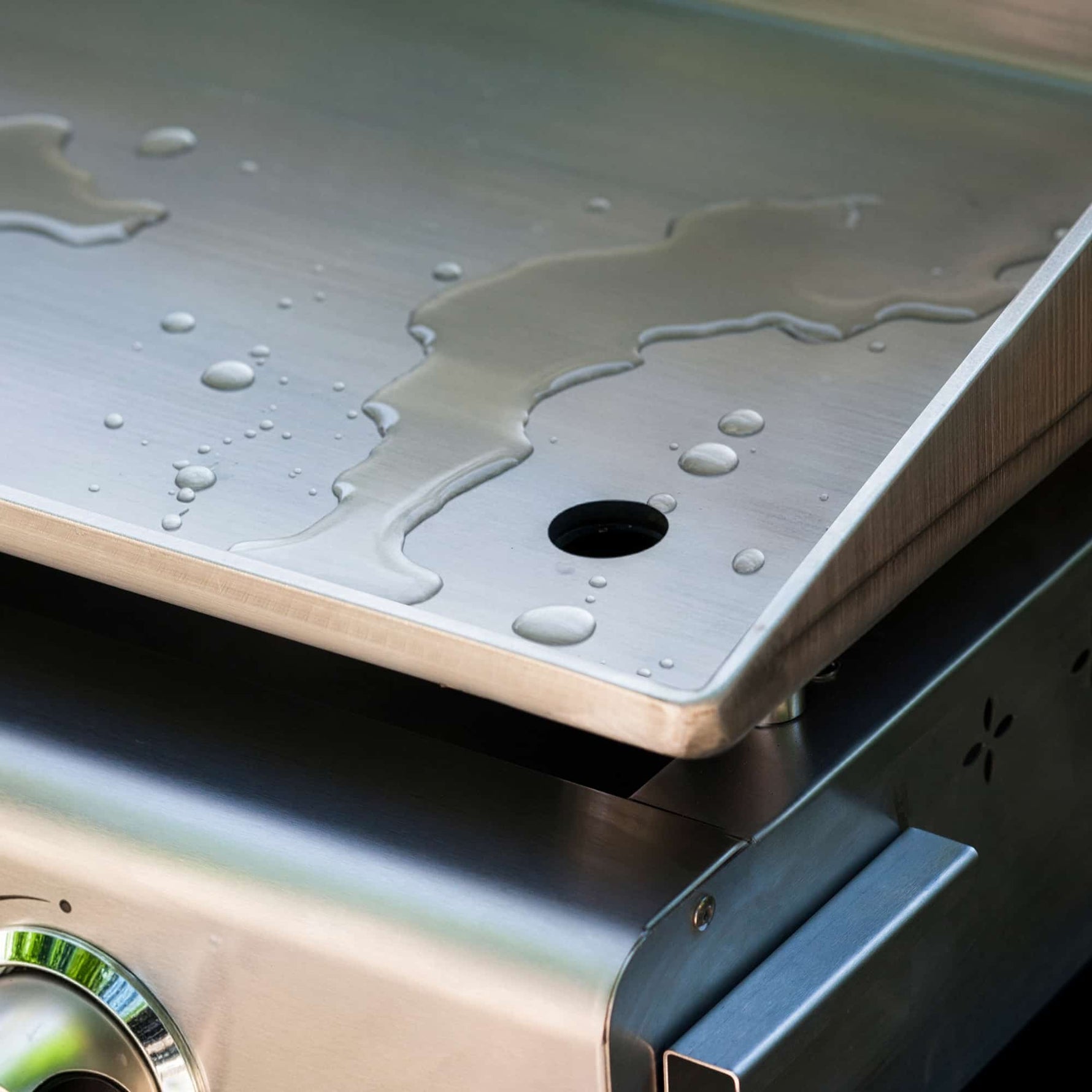 Rinsing the cooking plate of a Vivaplancha griddle with water for quick cleaning after use